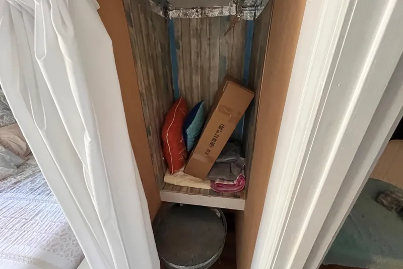 Slide: The Image of 1972 Whitcraft houseboat interior with storage area, pillows, and a cardboard box. - 15