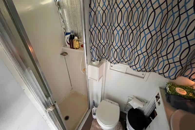 Slide: The Image of 1972 Whitcraft houseboat bathroom with shower, toilet, and patterned curtain. - 18