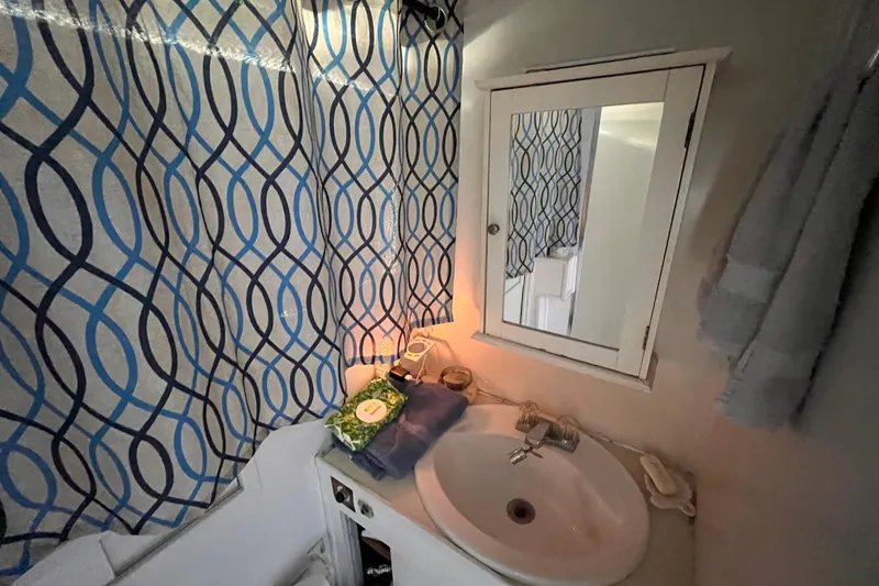 Slide: The Image of 1972 Whitcraft houseboat bathroom with sink, mirror, and patterned blue curtains. - 20