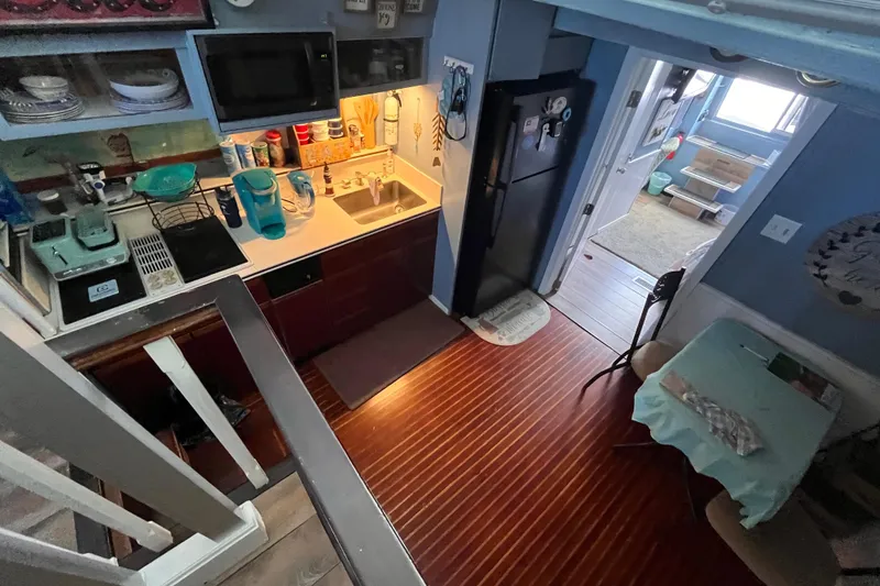 Slide: The Image of 1972 Whitcraft houseboat kitchen with wooden floors, compact appliances, and cozy dining area. - 9
