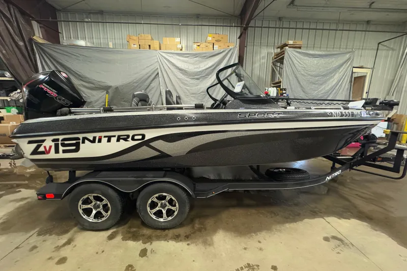 Slide: The Image of 2024 Nitro ZV19 Sport boat in a warehouse setting, side view. - 0