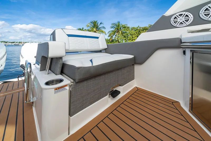 Slide: The Image of Manufacturer Provided Image: 2025 Tiara Yachts 34 LX interior with cushioned seating and teak flooring, docked by palm trees. - 10