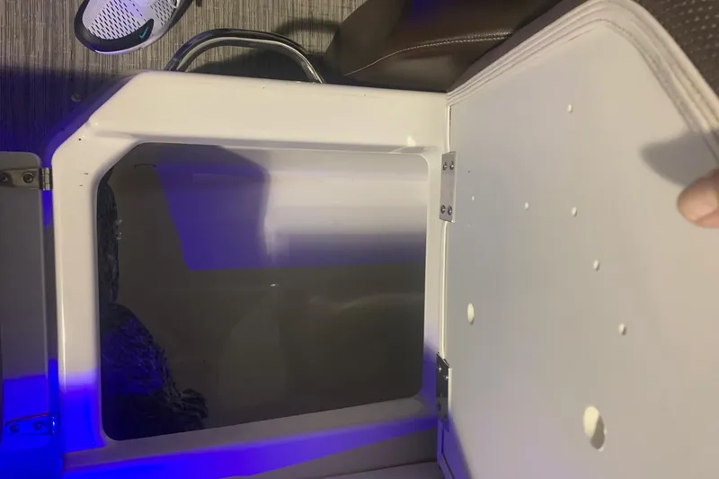 Slide: The Image of Open storage compartment in 2019 Scarab 255 Wake ID boat, with blue ambient lighting. - 24