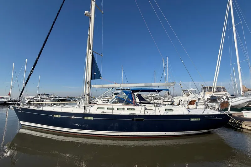 Slide: The Image of 2004 Beneteau 57 sailboat docked in marina under clear blue sky. - 1