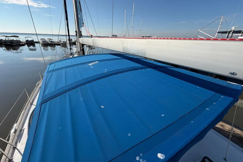Slide: The Image of 2004 Beneteau 57 sailboat with blue cover docked at marina. - 21