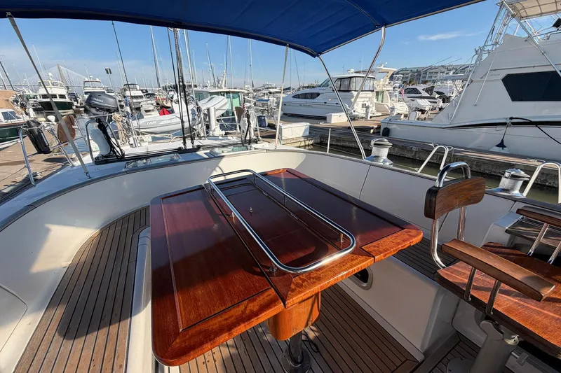 Slide: The Image of Cockpit of 2004 Beneteau 57 yacht with wooden table and marina view. - 30