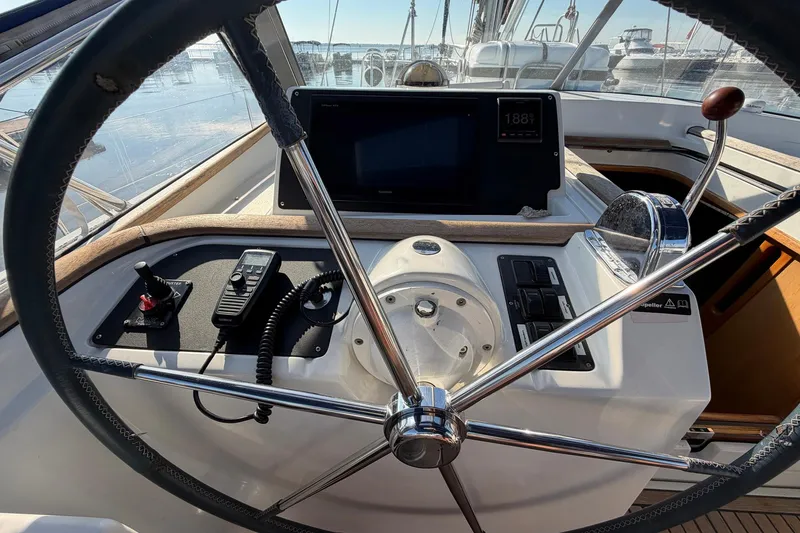 Slide: The Image of Steering wheel and controls of a 2004 Beneteau 57 yacht, featuring navigation equipment. - 32