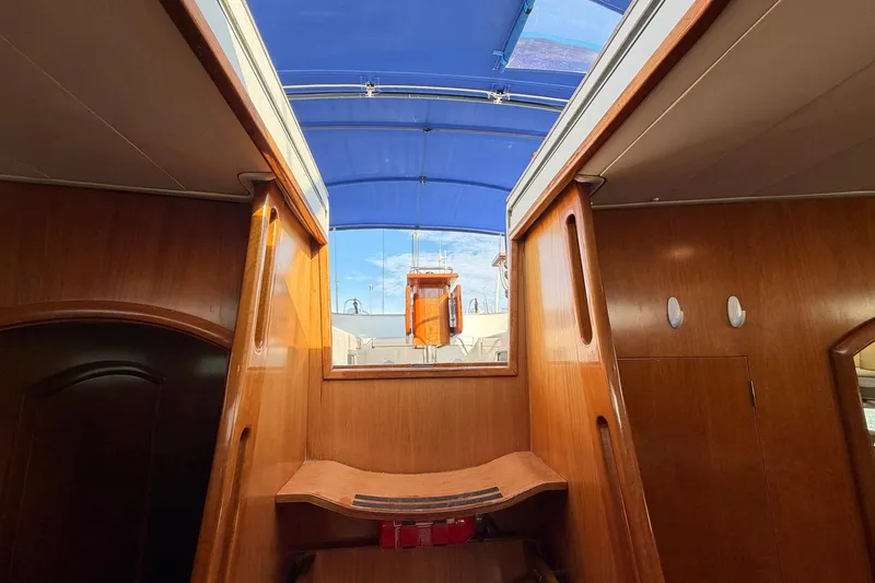 Slide: The Image of Interior view of 2004 Beneteau 57 sailboat with wooden finish and blue canopy. - 37