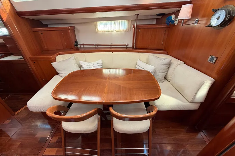 Slide: The Image of Luxurious 2004 Beneteau 57 yacht interior with elegant wooden dining area and plush seating. - 44