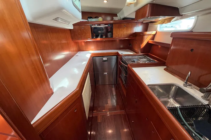 Slide: The Image of Luxurious 2004 Beneteau 57 yacht kitchen with wood cabinetry and modern appliances. - 47