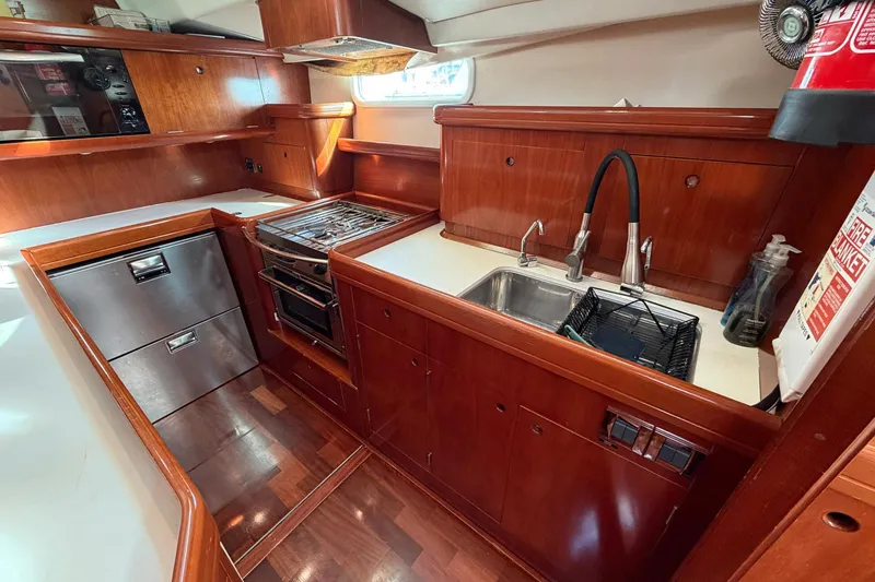 Slide: The Image of Luxurious 2004 Beneteau 57 yacht kitchen with wood cabinetry, stainless steel appliances, and modern fixtures. - 48