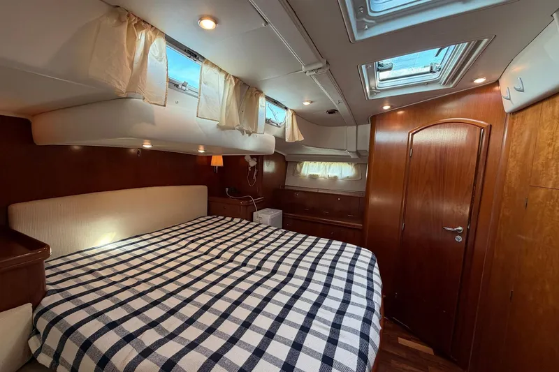 Slide: The Image of Luxurious 2004 Beneteau 57 yacht cabin with cozy bed and elegant wood finishes. - 54