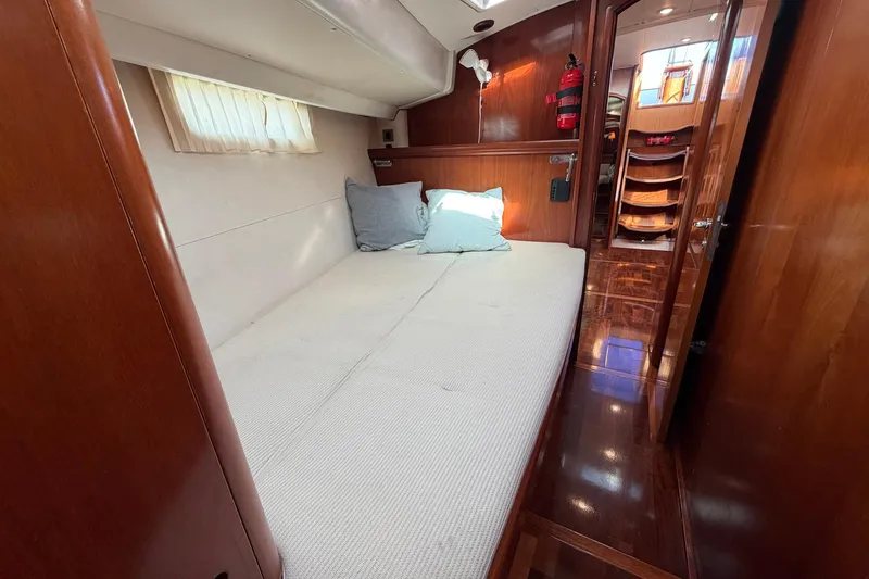 Slide: The Image of 2004 Beneteau 57 yacht cabin with cozy bed, wooden interior, and soft lighting. - 70