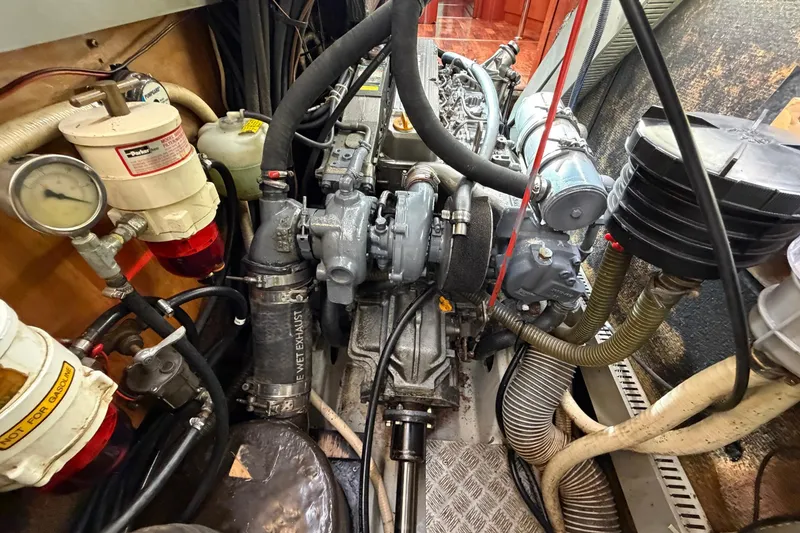 Slide: The Image of Engine room of a 2004 Beneteau 57 yacht, showcasing mechanical components and hoses. - 79