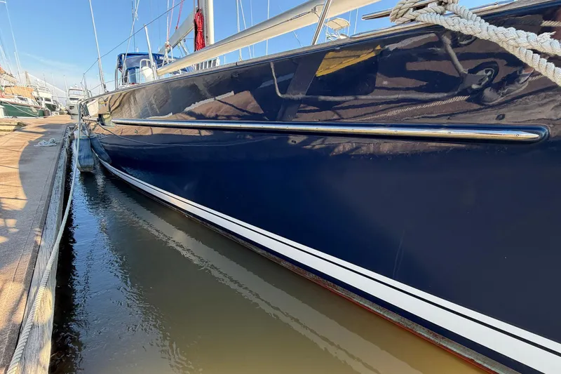 Slide: The Image of 2004 Beneteau 57 yacht docked, showcasing sleek blue hull and polished details. - 9
