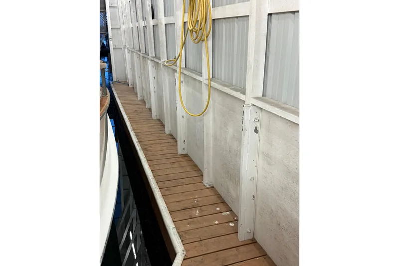 Slide: The Image of Narrow wooden dock beside a 1981 Grand Banks 42 Classic boat in a boathouse. - 10