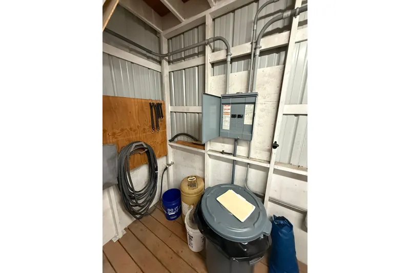 Slide: The Image of Utility room with electrical panel, cables, and storage bins on wooden floor. Grand Banks 42 Classic, 1981. - 12