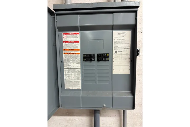 Slide: The Image of Electrical panel with open door, showing circuit breakers and safety labels, Grand Banks 42 Classic 1981. - 13
