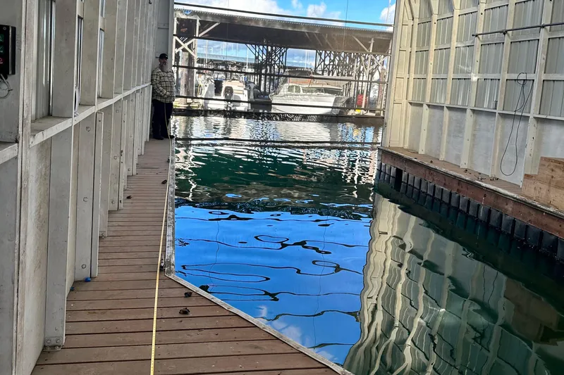 Slide: The Image of Indoor marina with a 1981 Grand Banks Classic Tri-cabin yacht docked, reflecting on water. - 3