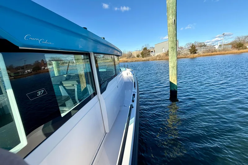 Slide: The Image of 2021 Axopar 37 XC Cross Cabin boat on calm water near a dock. - 10