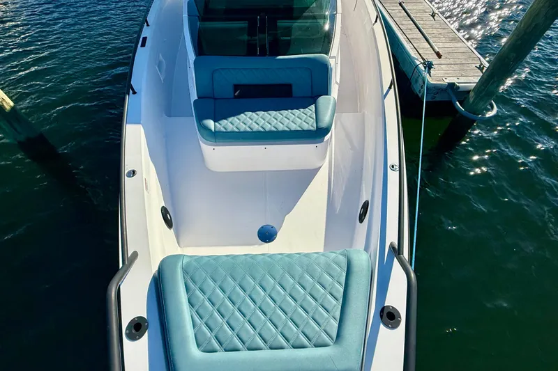 Slide: The Image of 2021 Axopar 37 XC CROSS CABIN boat with teal seating, docked on calm water. - 6