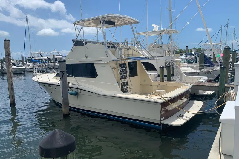 The Image of 1985 Hatteras 36 Convertible yacht docked at a marina under a clear blue sky. - 0