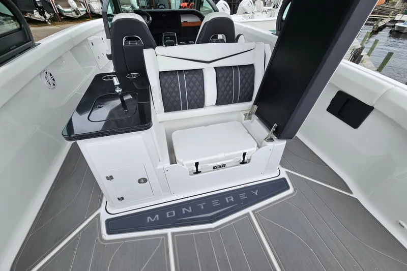 Slide: The Image of 2026 Monterey Elite 30 OB boat interior with seating and sink, docked by the water. - 12