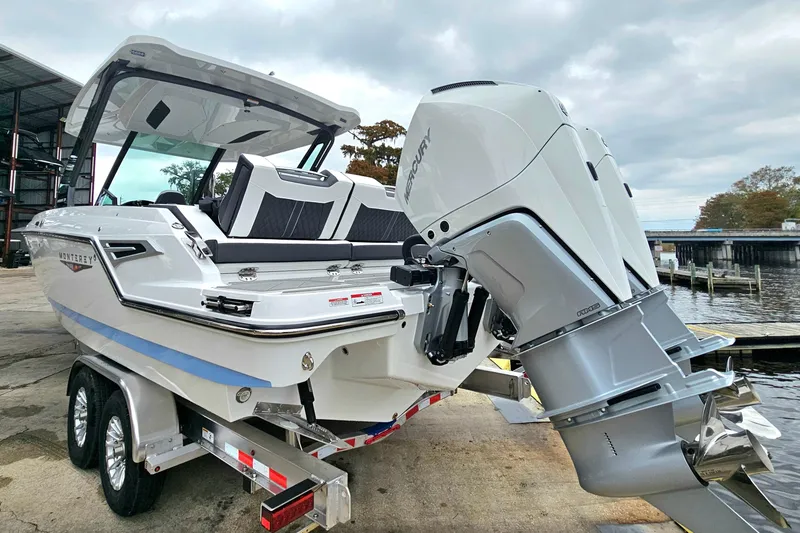 Slide: The Image of 2026 Monterey Elite 30 OB boat with Mercury outboard engine on trailer by waterfront. - 2
