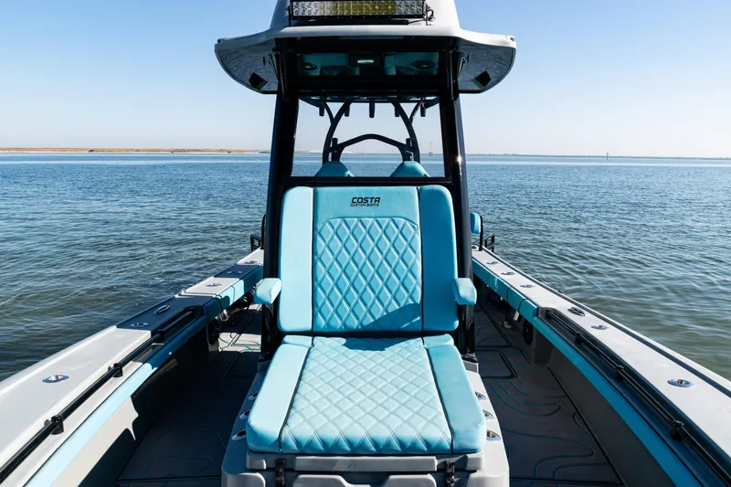 Slide: The Image of 2022 Costa Custom Boats 264 on calm water, featuring blue seating and sleek design. - 18