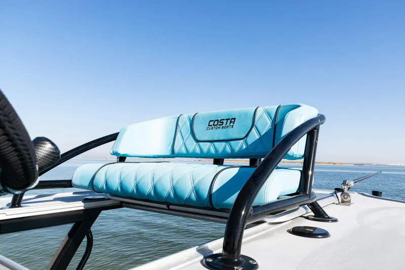 Slide: The Image of Costa Custom Boats 264, 2022 model, featuring blue seating on a sunny day at sea. - 19