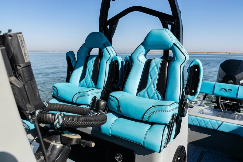 Slide: The Image of Luxurious blue seats on a 2022 Costa Custom Boats 264, with a scenic water backdrop. - 22