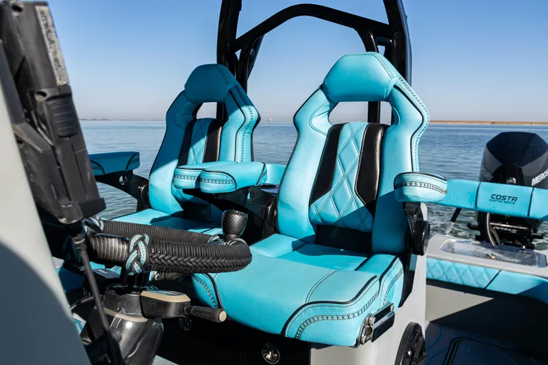 Slide: The Image of 2022 Costa Custom Boats 264 interior with blue and black seating on calm water. - 46