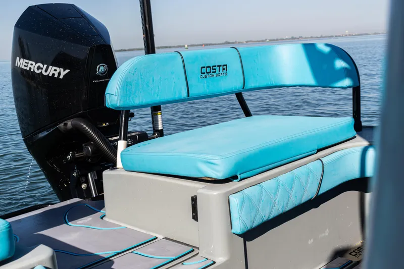 Slide: The Image of 2022 Costa Custom Boats 264 with blue seating and Mercury engine on calm water. - 56