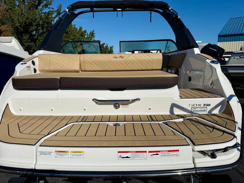 Slide: The Image of The image shows the stern of a 2026 Sea Ray SDX 230 boat with beige upholstery. - 2
