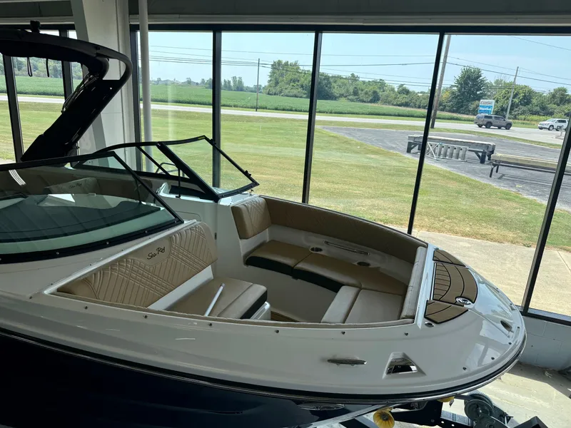 Slide: The Image of 2026 Sea Ray SDX 230 in a showroom with cushioned seating and large windows. - 14