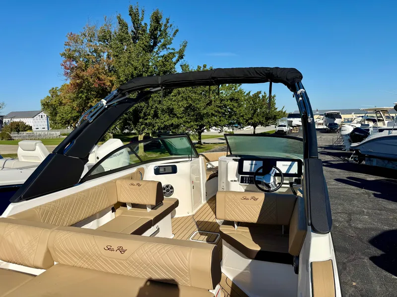 Slide: The Image of The image shows a Sea Ray SDX 230 boat with beige seating and a black bimini top. - 6