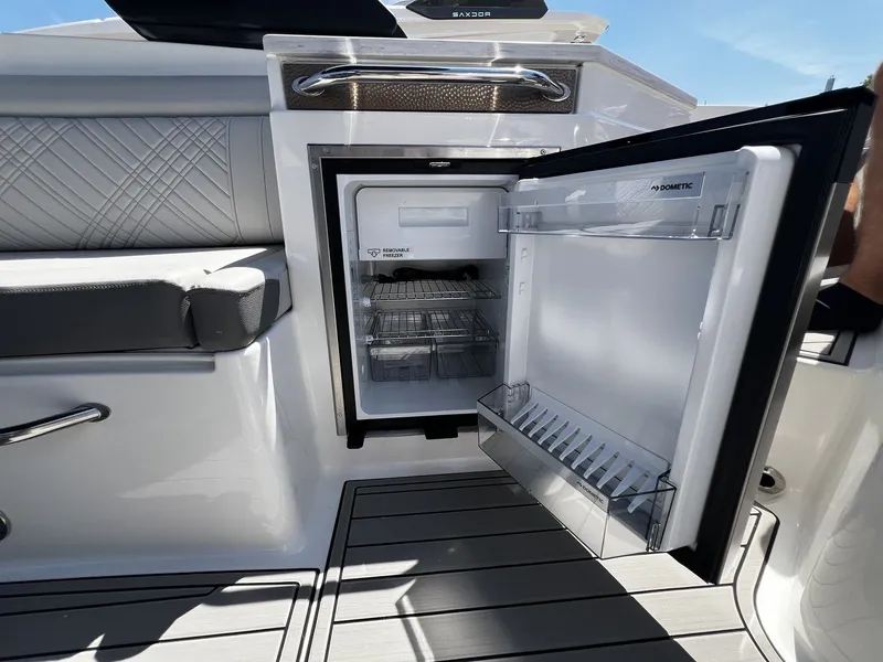 Slide: The Image of Open refrigerator on a Sea Ray SDX 290 boat, featuring gray upholstery and wooden flooring. - 27