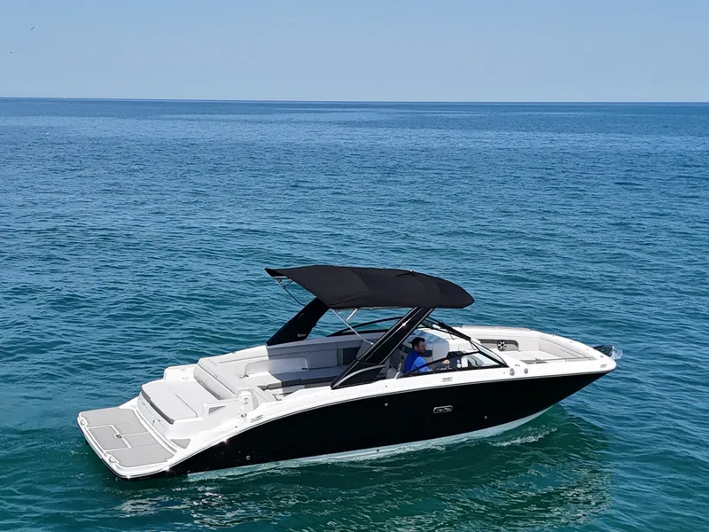 Slide: The Image of A sleek 2026 Sea Ray SDX 290 boat on calm blue water with a black canopy. - 9