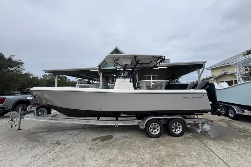 The Image of 2026 Sea Born LX26 Center Console boat on trailer, parked outdoors. - 1