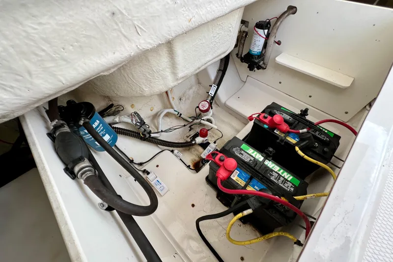 Slide: The Image of 2024 Robalo R230 Center Console boat battery compartment with wiring and components. - 13