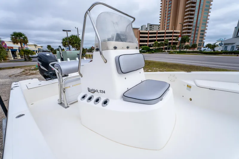 Slide: The Image of 2005 BlackJack 224 boat with seating, parked near a road and buildings. - 15