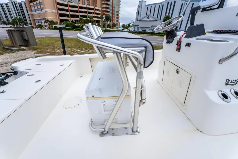 Slide: The Image of 2005 BlackJack 224 boat interior with seating and steering console, docked near buildings. - 17