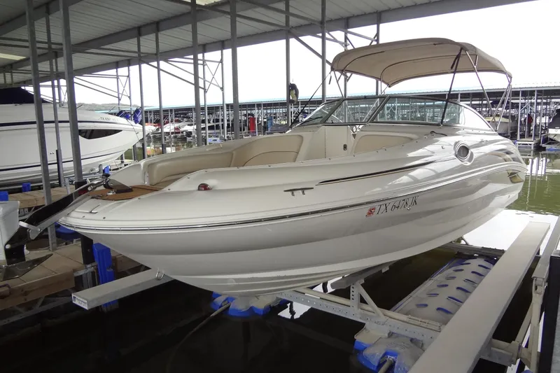 The Image of 2000 Sea Ray 240 Sundeck boat docked in a marina under a covered structure. - 0
