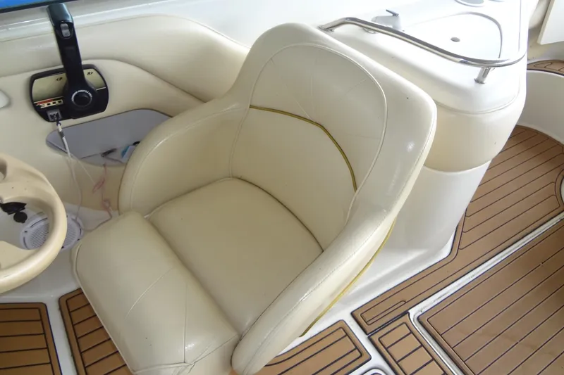 Slide: The Image of Captain's seat on 2000 Sea Ray 240 Sundeck with beige upholstery and wood-patterned flooring. - 11