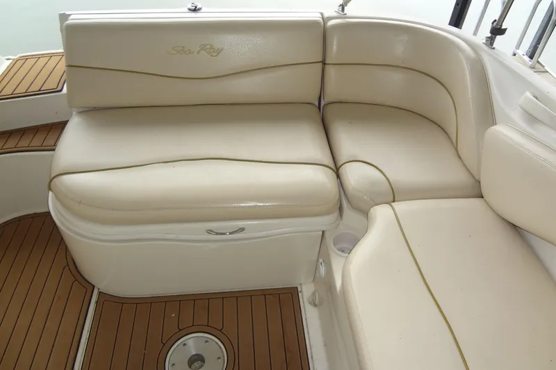 Slide: The Image of 2000 Sea Ray 240 Sundeck interior seating with beige upholstery and wooden flooring. - 17