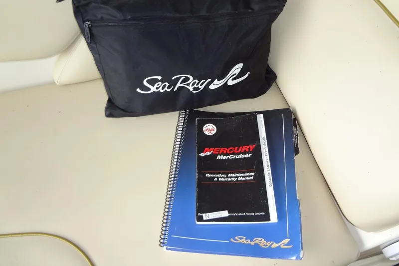 Slide: The Image of Sea Ray 240 Sundeck 2000 manuals and bag on boat seat. - 23