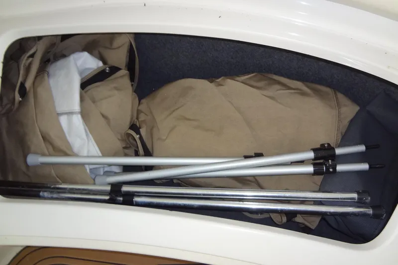 Slide: The Image of Storage compartment of 2000 Sea Ray 240 Sundeck with folded canvas and poles. - 25