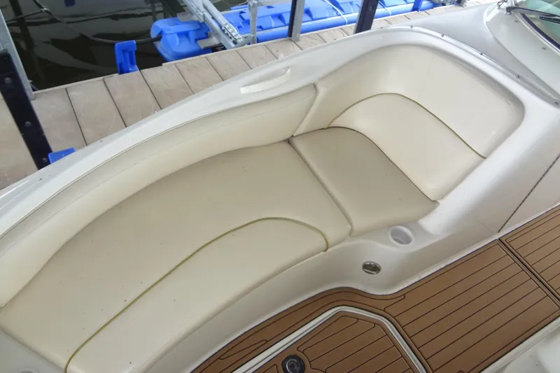Slide: The Image of 2000 Sea Ray 240 Sundeck boat interior with cream seating and wooden deck. - 9