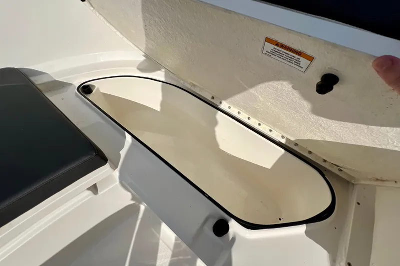 Slide: The Image of 2023 Trophy T24CC boat storage compartment with open lid and warning label. - 22