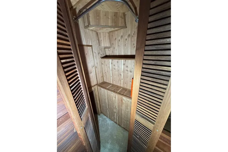 Slide: The Image of Wooden closet interior on 1986 Bluewater 46 MY yacht, featuring shelves and hanging rod. - 13